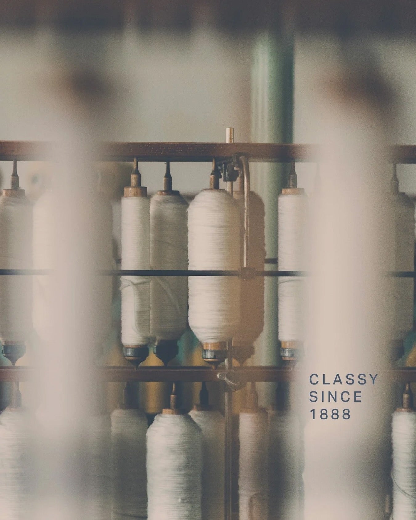 Spinning machine with yarn spools and 'Classy Since 1888' text.