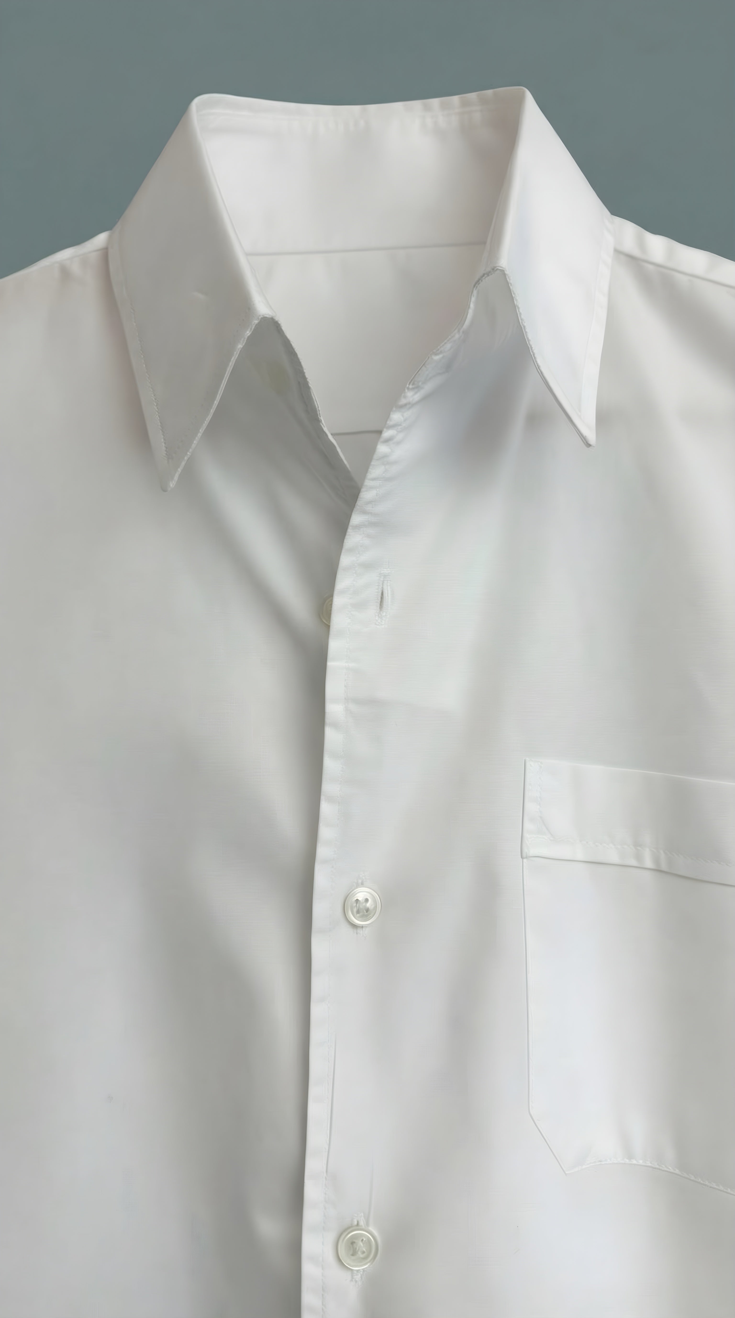 Close-up of a white men shirt with a collar and button details 
