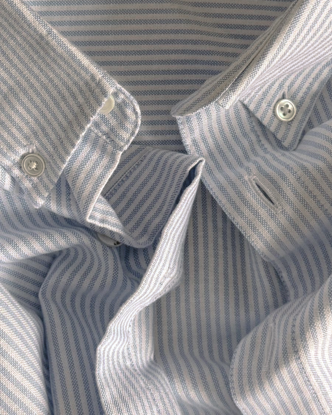 Close-up of a blue and white striped Oxford shirt with buttons.