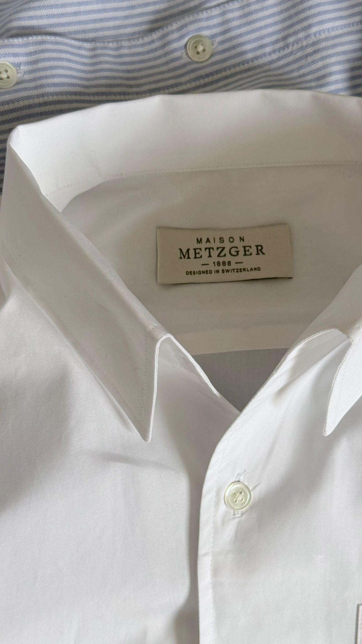 Close-up of a white men shirt with a Maison Metzger label.